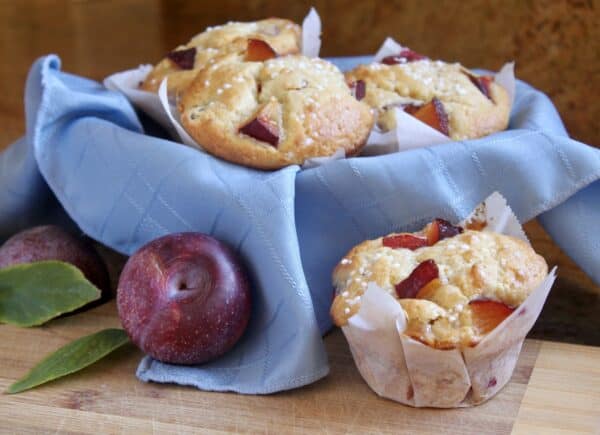 basket of plum muffins with a plum nearby