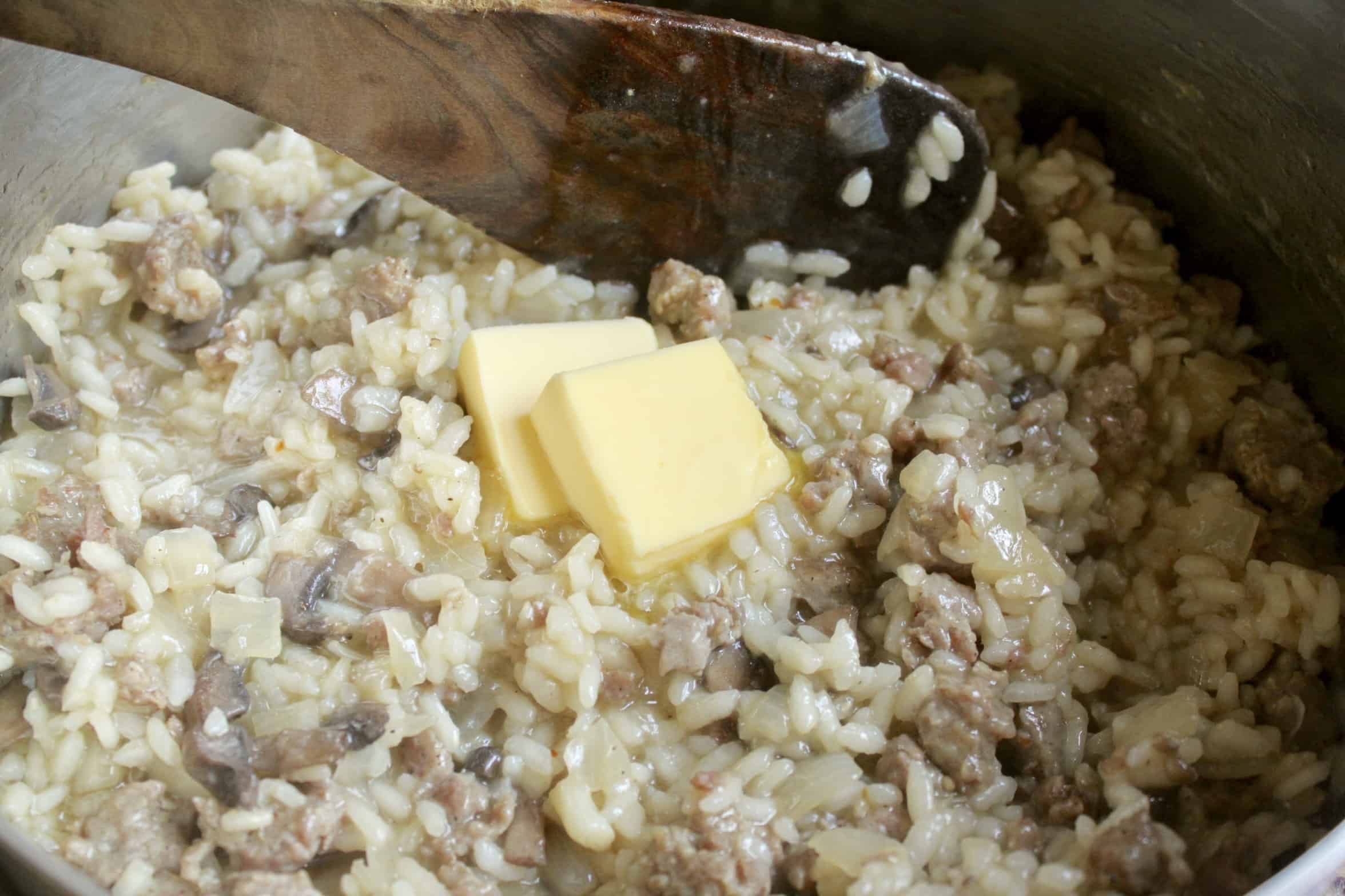 adding butter to sausage and mushroom risotto