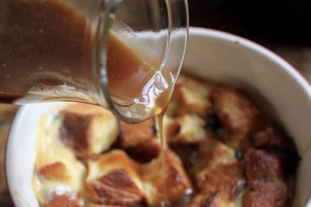 pouring Whisky sauce over bread pudding 
