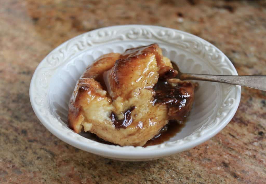 bread and butter pudding with whisky sauce in a small bowl with a spoon