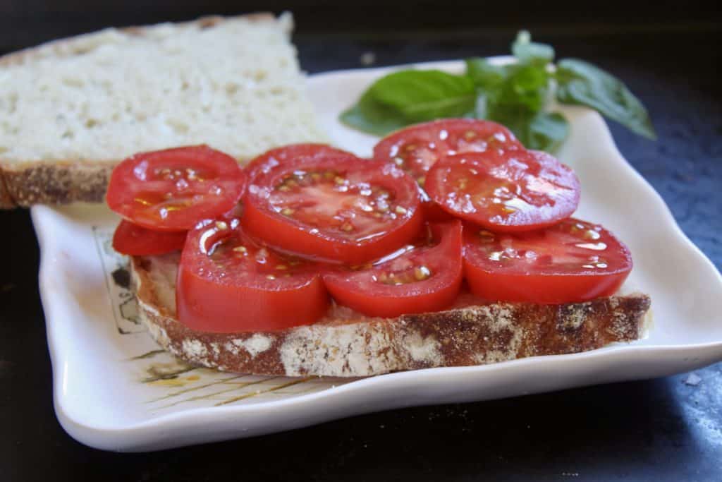 adding tomatoes to the bread