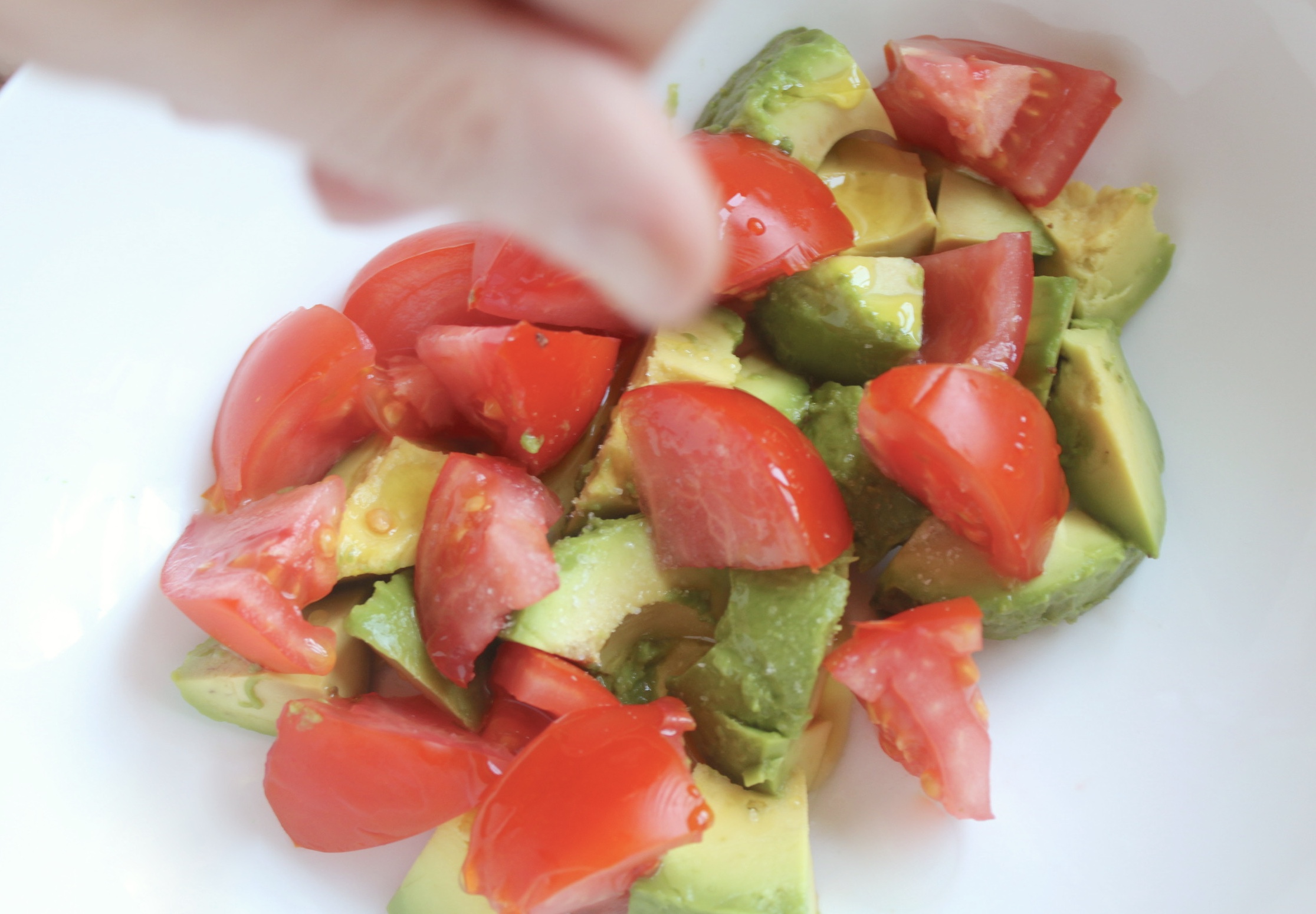 adding salt to avocado and tomato salad