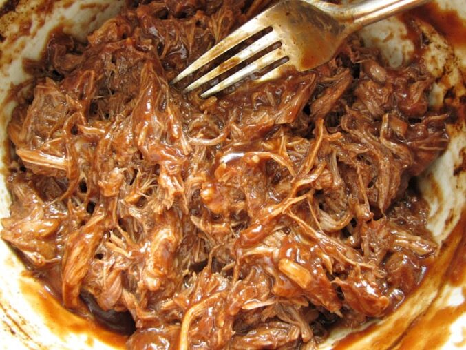 bbq pulled pork crock pot recipe stirring pulled pork with fork