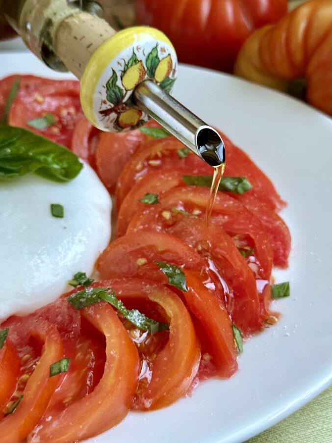 pouring olive oil on Caprese