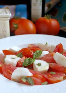 caprese sald with tomatoes in background