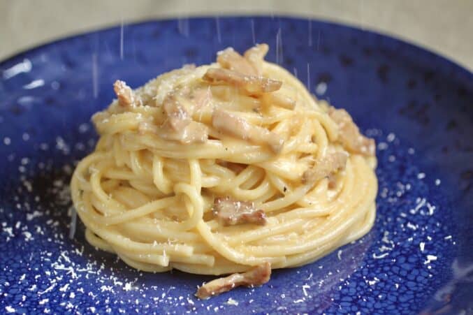 grating cheese on spaghetti alla carbonara