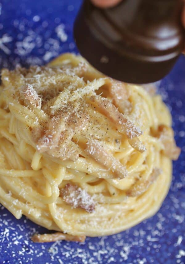 grating pepper on pasta carbonara