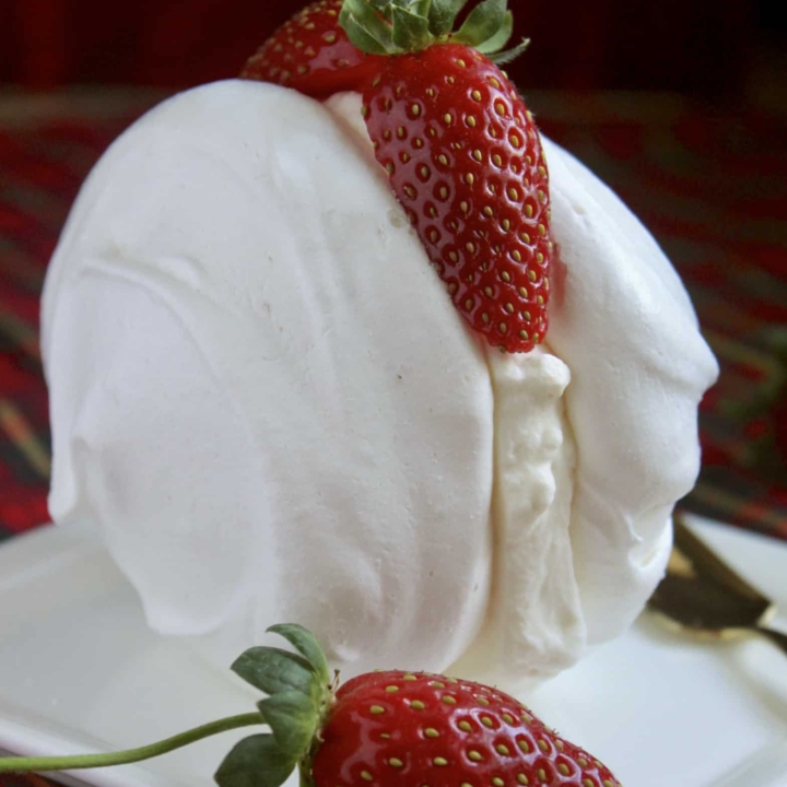 Meringues with cream and strawberries on a plate