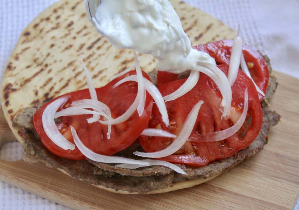 assembling a gyro with meat, tomatoes and onion