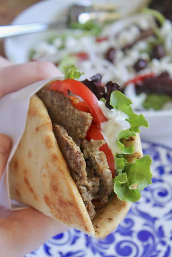 handheld homemade Greek gyro sandwich in a pita