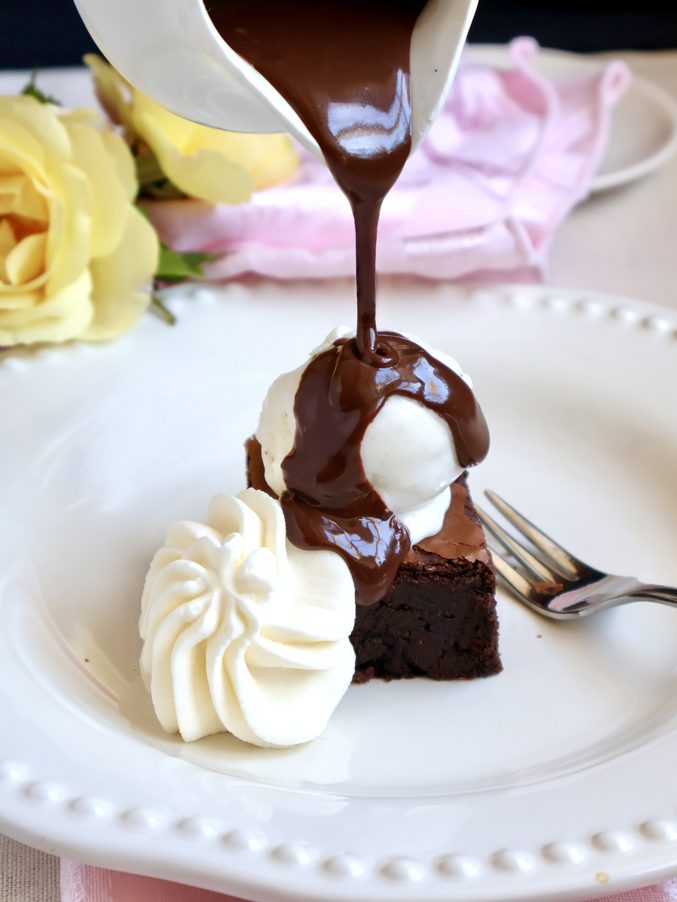 pouring chocolate over ice cream and brownie