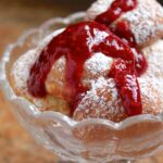 aebleskivers in a bowl with raspberry sauce