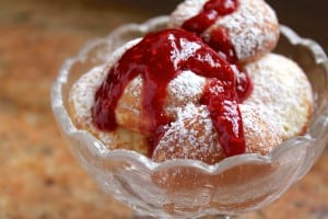 aebleskivers in a bowl with raspberry sauce