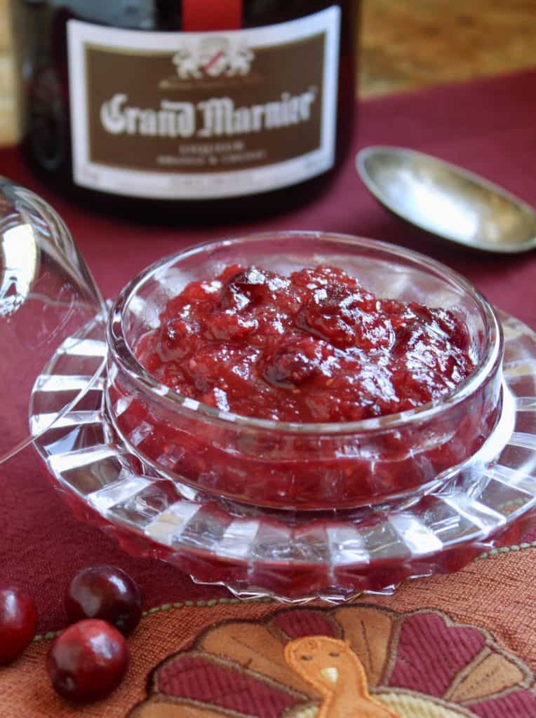 Orange Cranberry Sauce with Grand Marnier in a glass bowl with a bottle of liqueur in the background