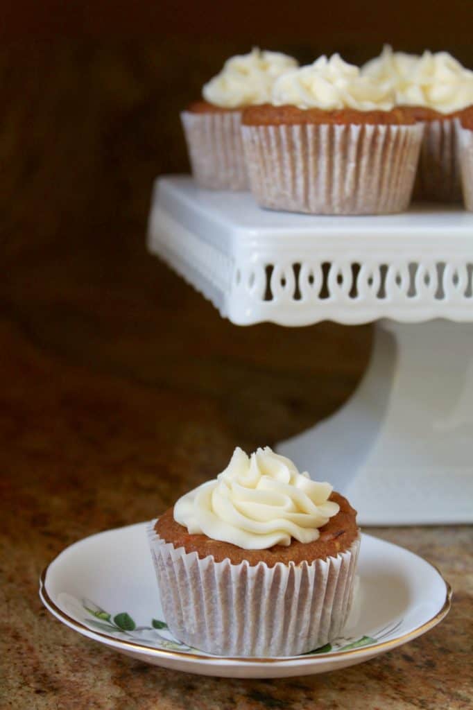 pumpkin muffins with cream cheese frosting on a cake stand and saucer