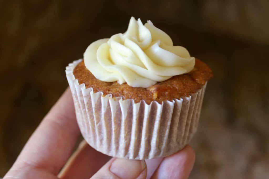 photo of hand with pumpkin carrot cupcake with cream cheese frosting