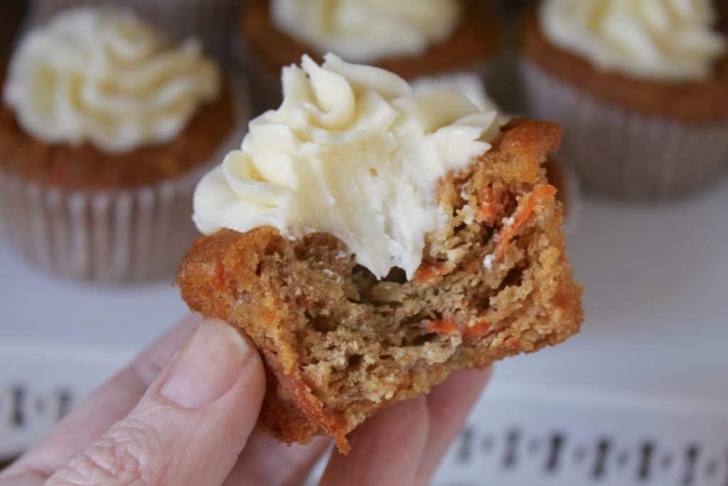 half eaten pumpkin muffin with cream cheese frosting held in hand