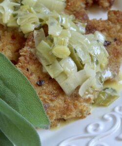 turkey cutlets with leeks and sage butter sauce on a platter with sage
