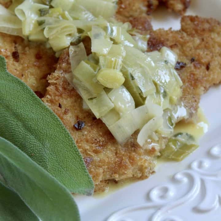 turkey cutlets with leeks and sage butter sauce on a platter with sage