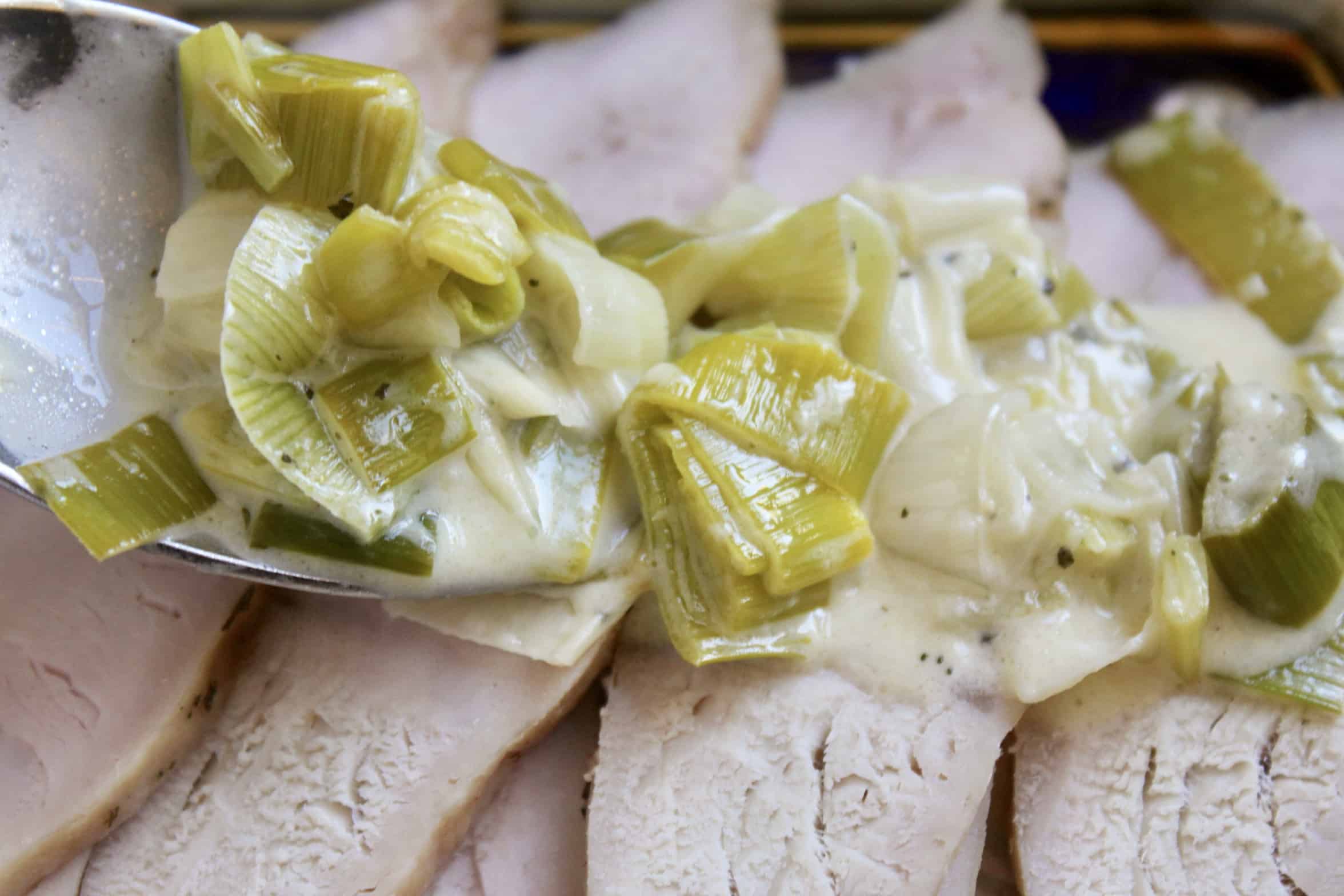 pouring leek sauce over turkey breast 