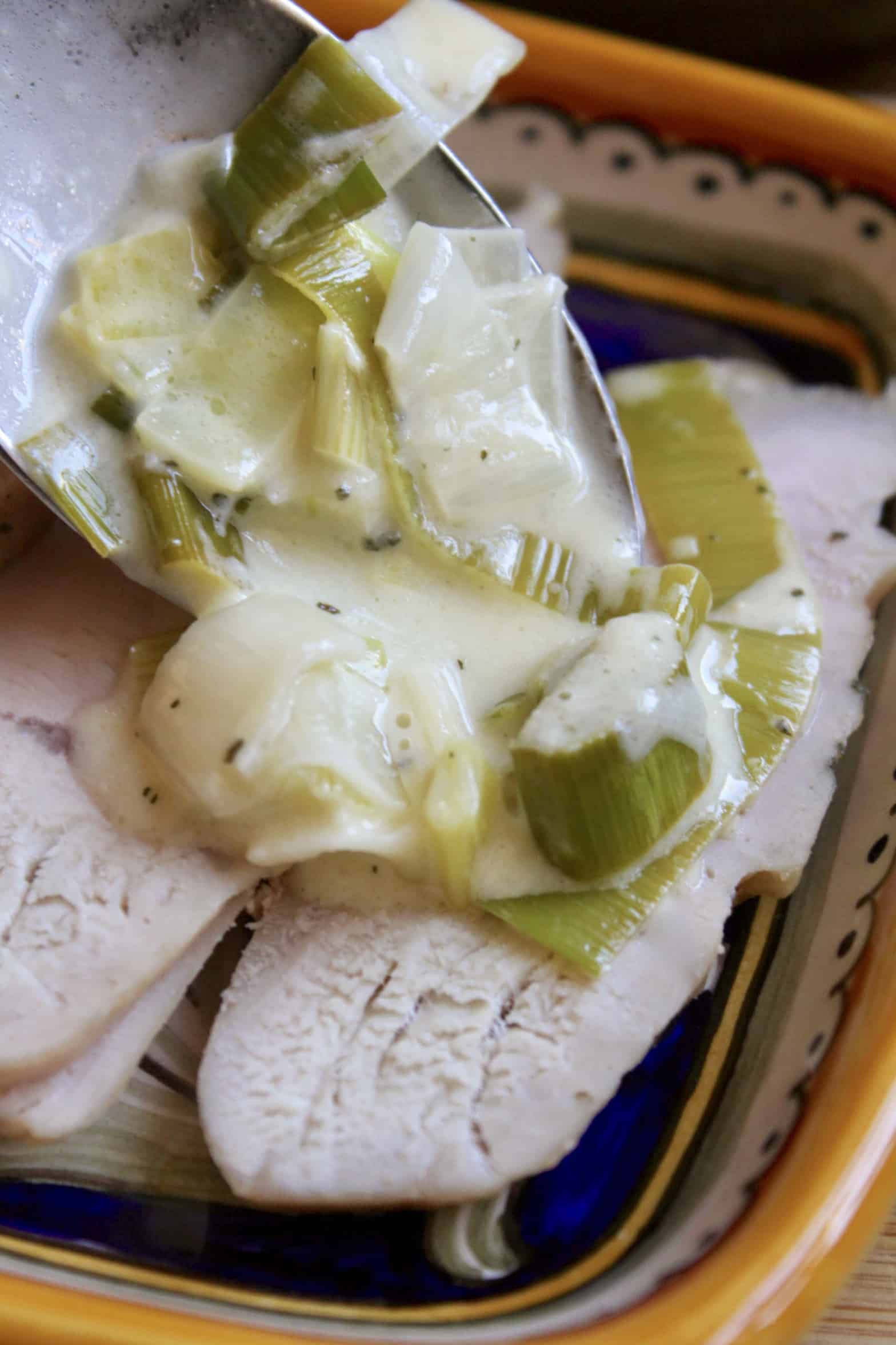 pouring leek sauce over turkey breast 