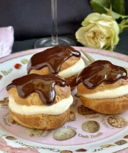 3 profiteroles on a plate with a rose