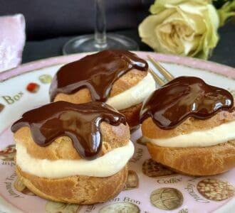 3 profiteroles on a plate with a rose