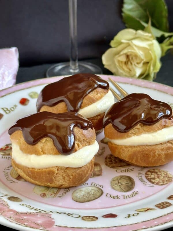3 profiteroles on a plate with a rose