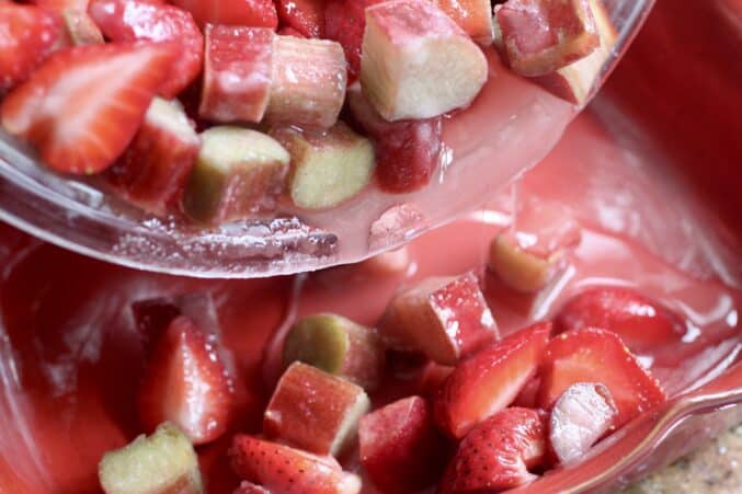 pouring strawberries and rhubarb into cobbler dish