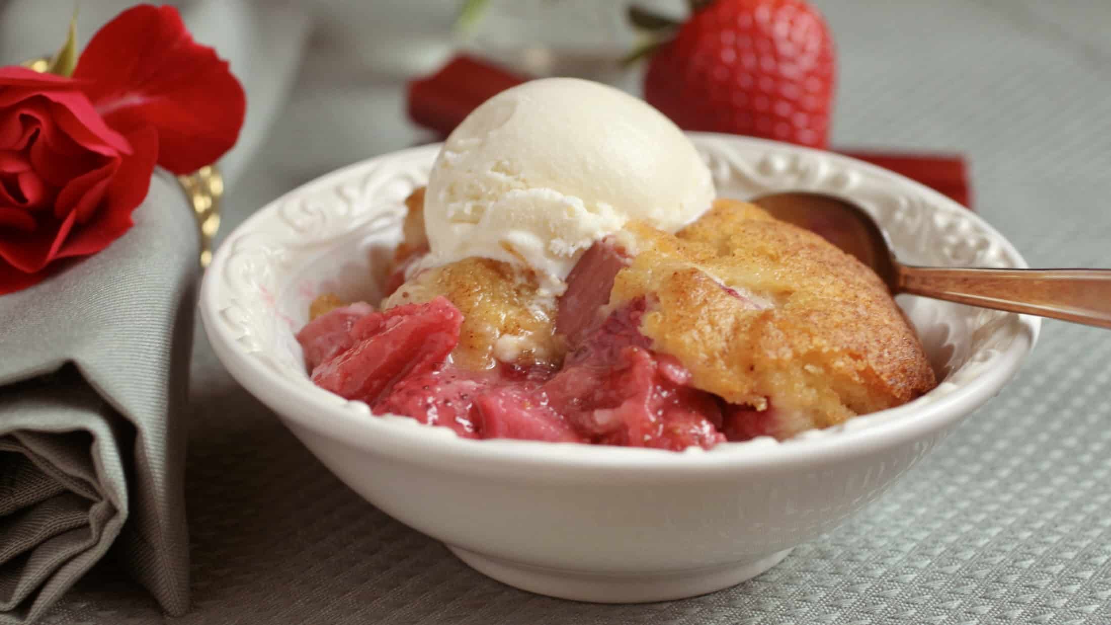 strawberry rhubarb cobbler in a bowl with ice cream