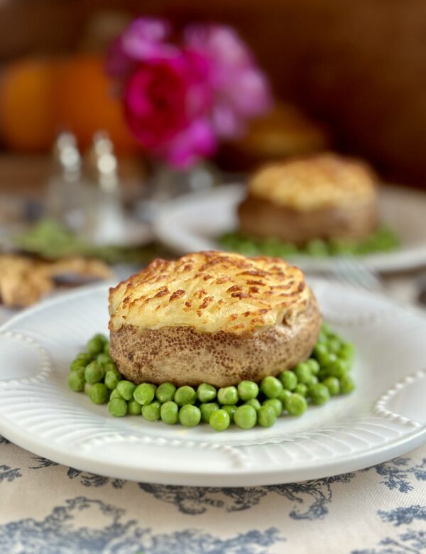 shepherd's pie baked potatoes on plate surrounded by peas