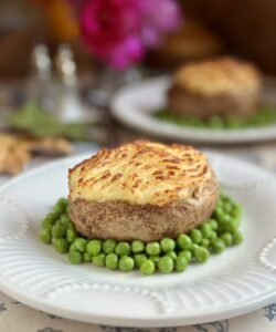 shepherd's pie baked potatoes on plate surrounded by peas