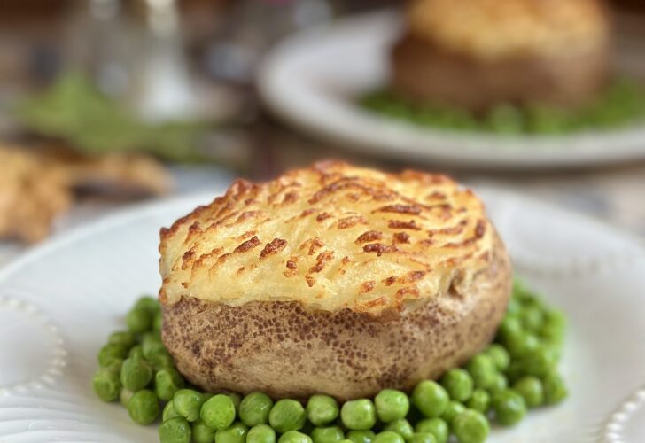 shepherd's pie baked potatoes on plate surrounded by peas