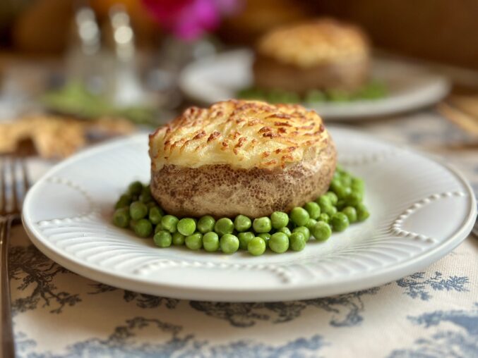 shepherd's pie baked potatoes on plate surrounded by peas