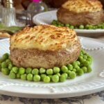 shepherd's pie baked potatoes on plate surrounded by peas