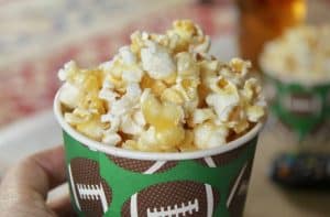 handheld cup of caramel crunch popcorn