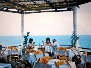 Vintage photo of three people on a veranda eating in Italy near the sea