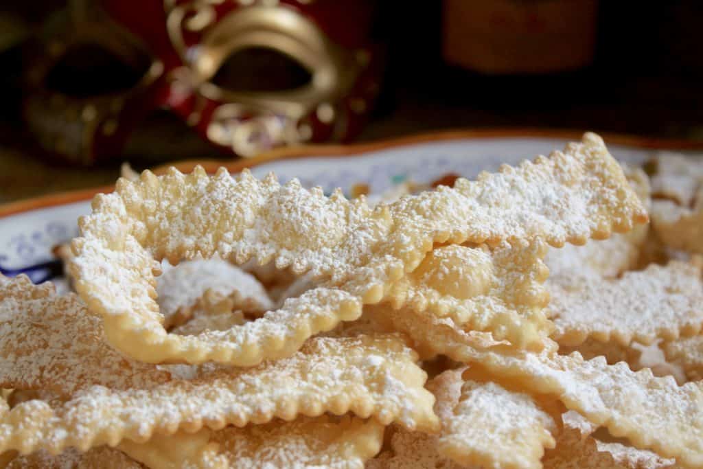 Italian bow tie cookies with Venetian carnevale mask in background