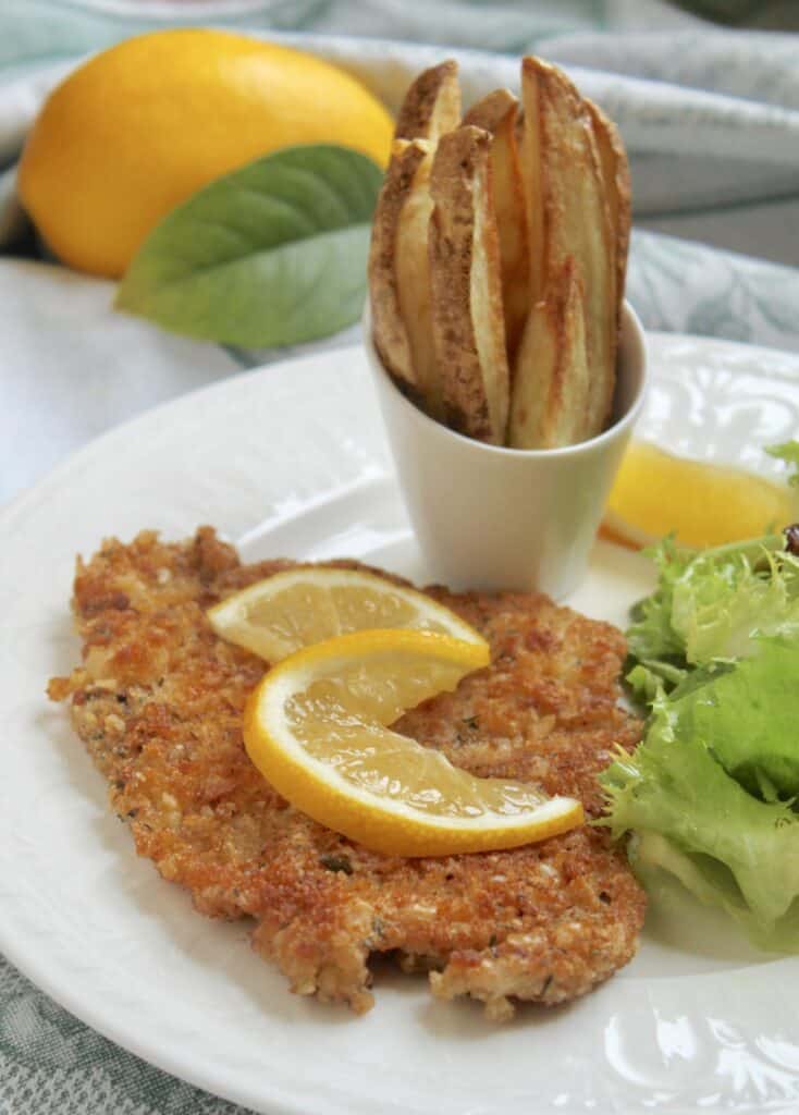 pork schnitzel with lemon slices salad and chips