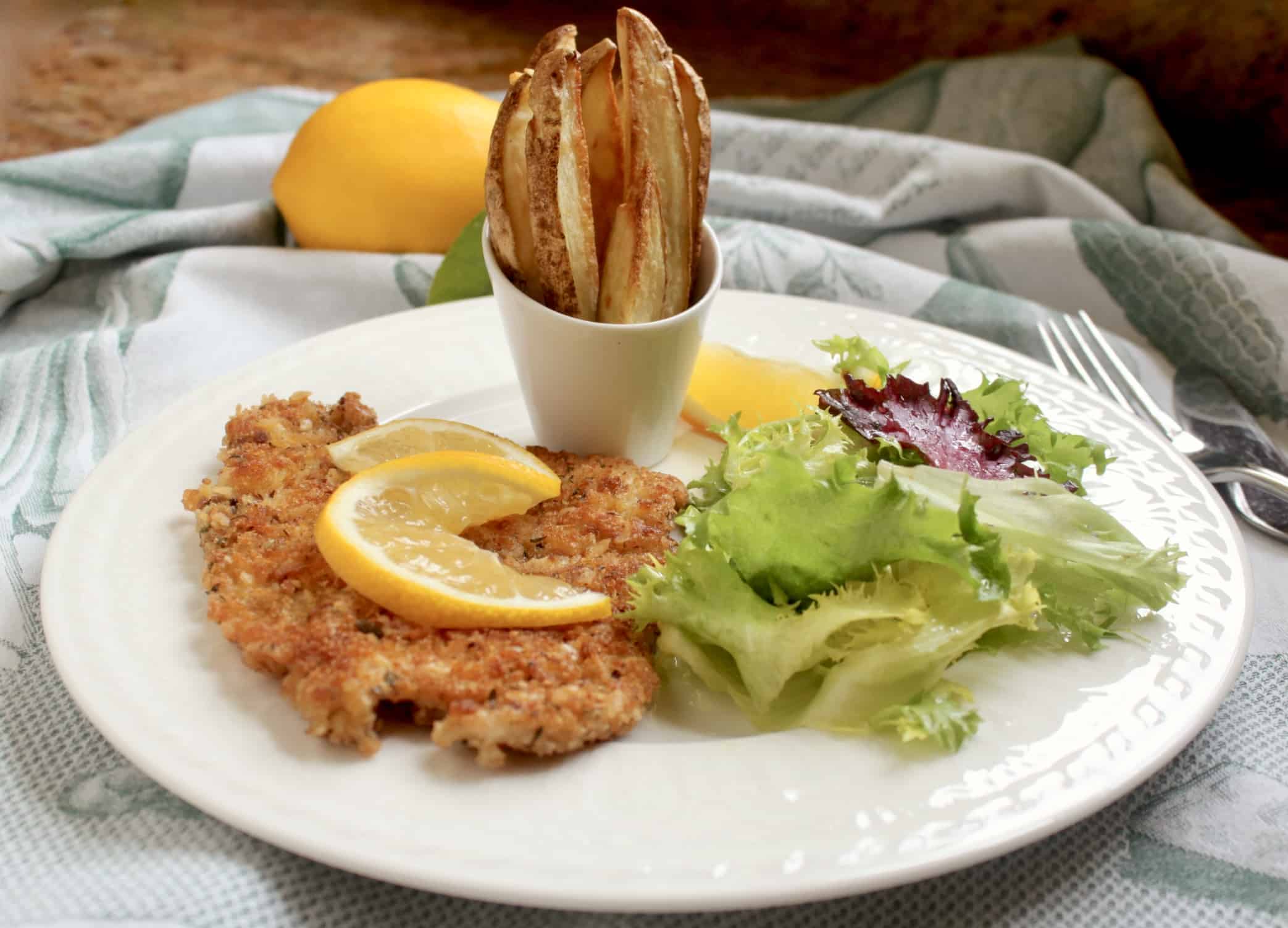 pork schnitzel on a plate with fries and salad
