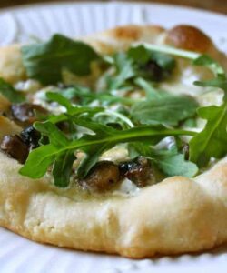 making a pizza with truffle creme fraiche, brie, mushrooms and arugula