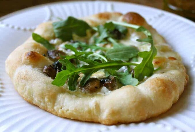 making a pizza with truffle creme fraiche, brie, mushrooms and arugula