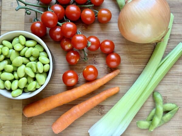 soybeans, carrots, tomatoes, celery and onion on a wooden board