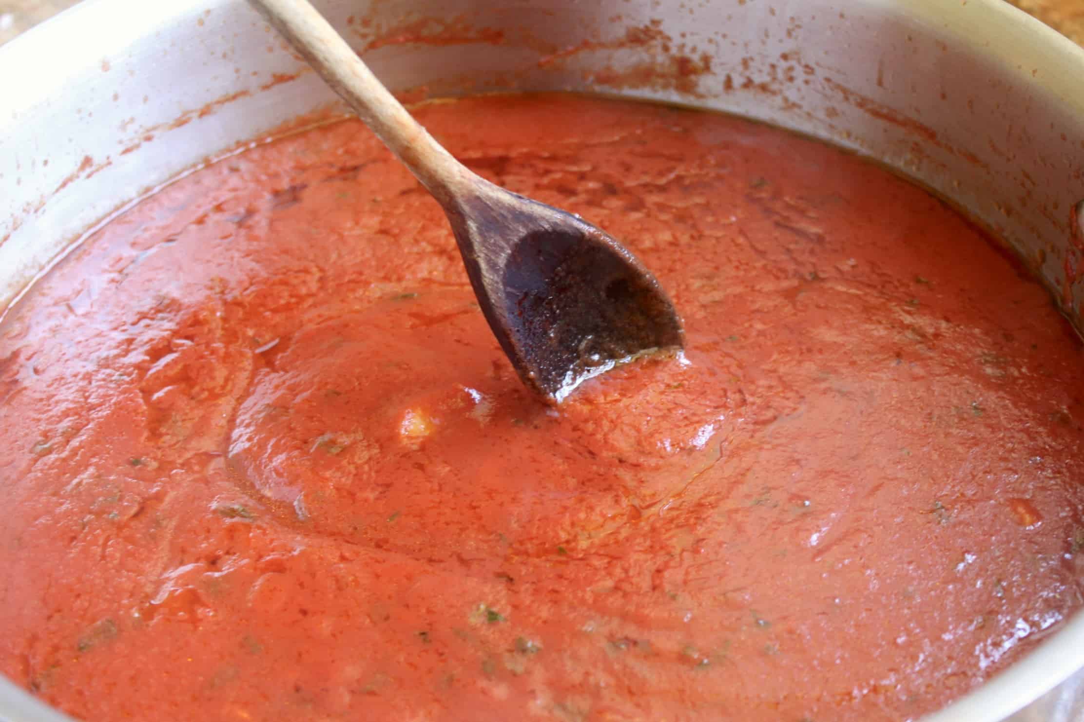 stirring italian tomato sauce with a wooden spoon