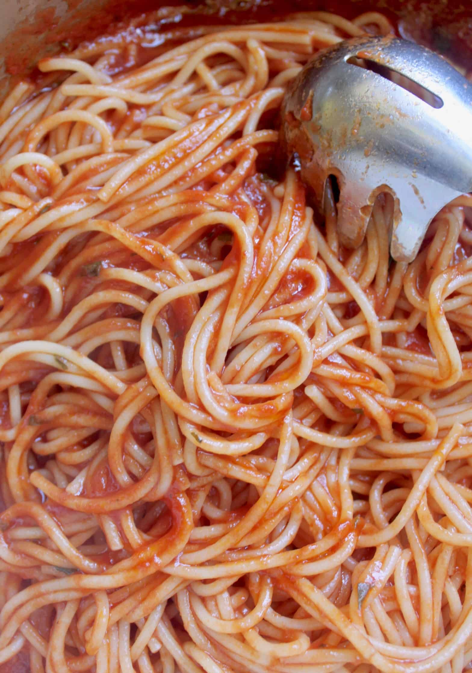mixing spaghetti with italian tomato sauce