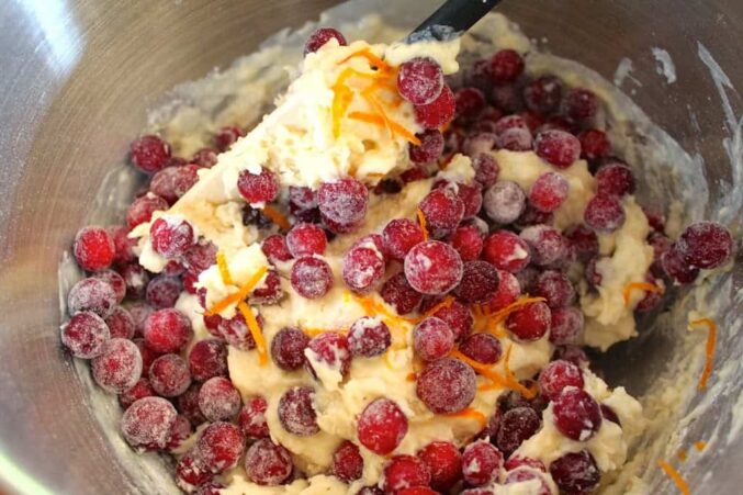 adding cranberries to batter for cranberry orange muffin recipe