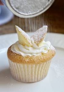 shaking confectioner's sugar on butterfly cupcakes