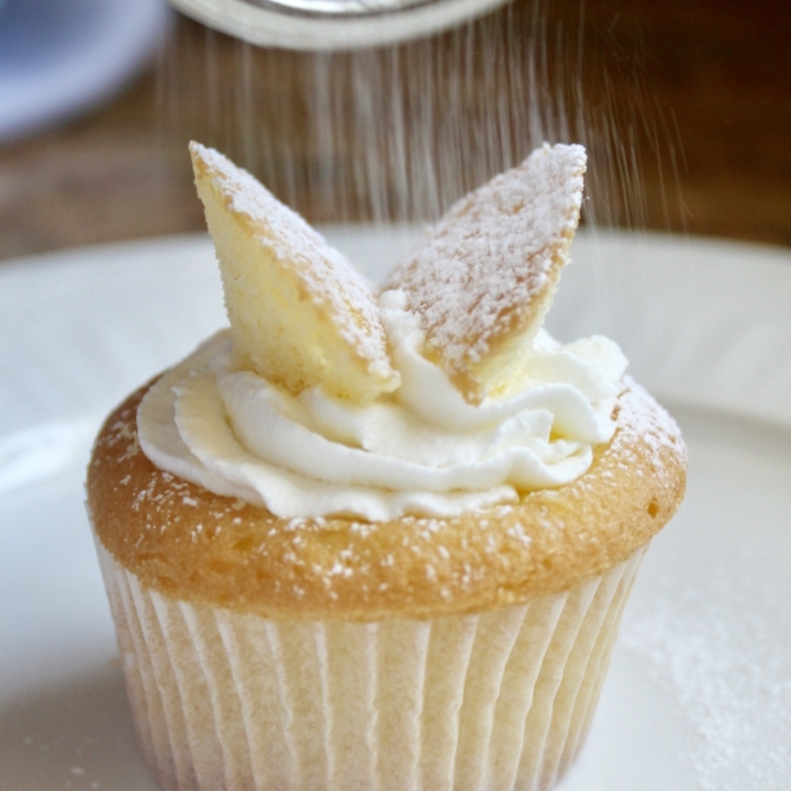 shaking confectioner's sugar on butterfly cupcakes