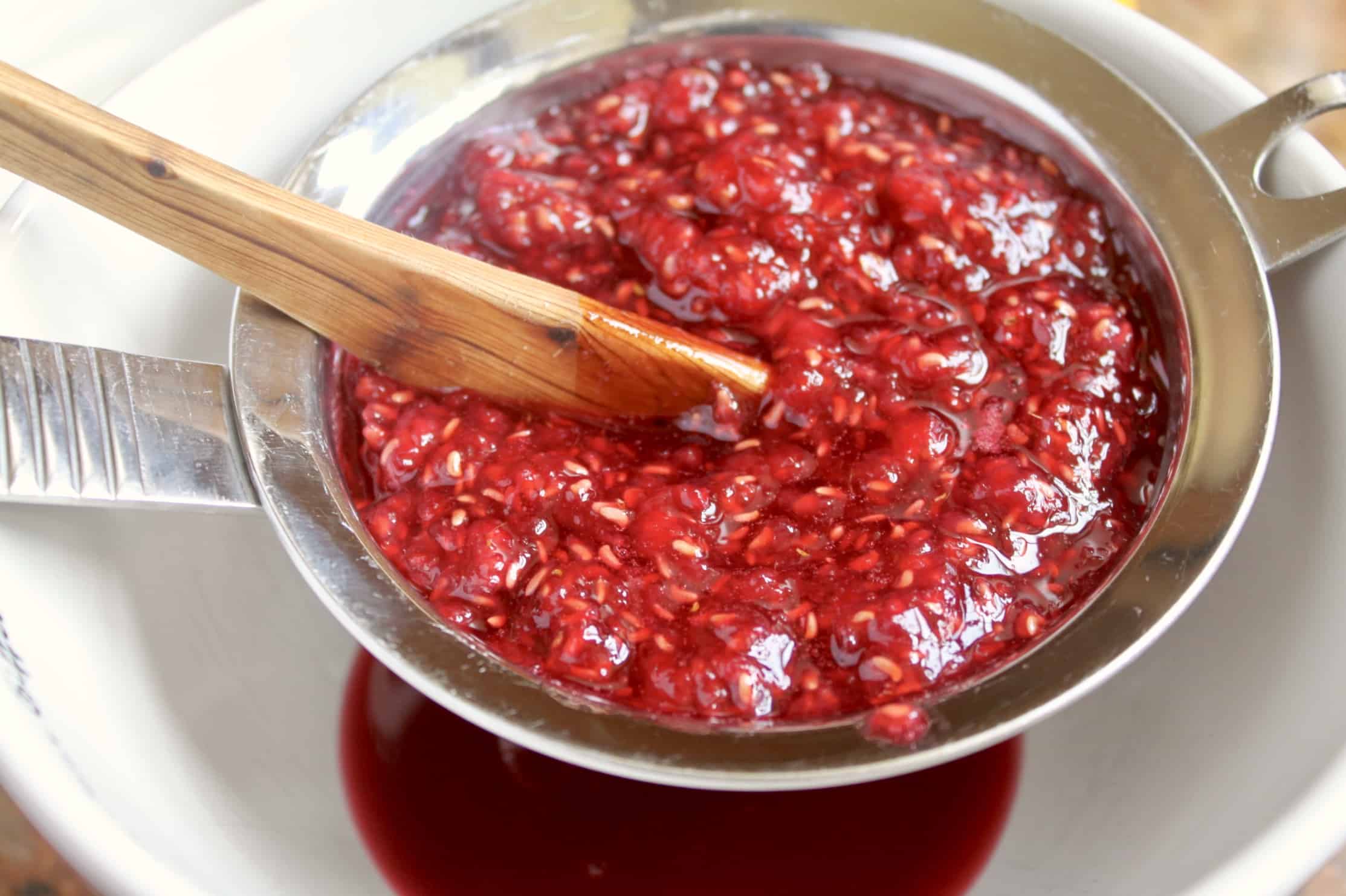 straining rasberries to make syrup