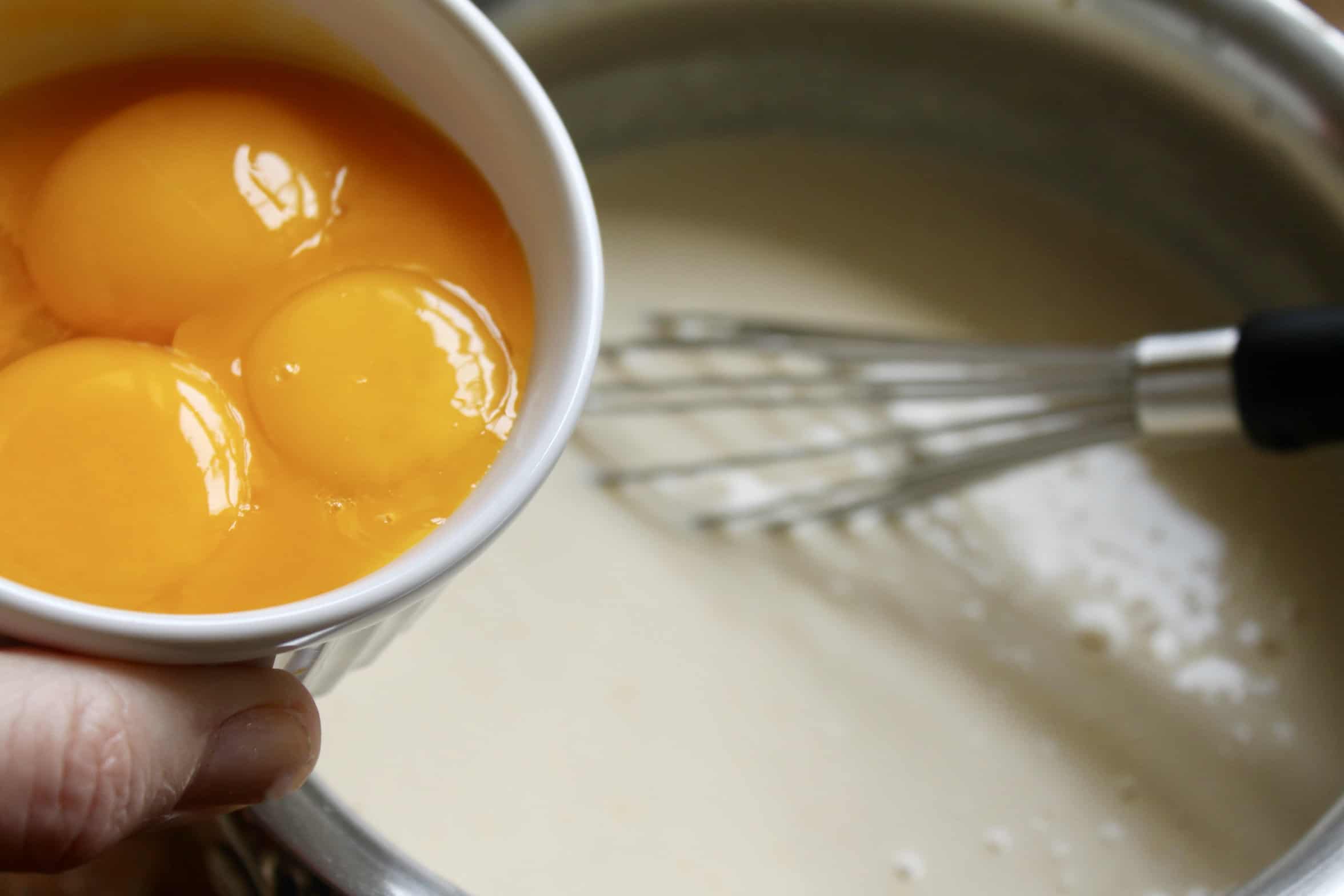 adding egg yolks to batter in pot
